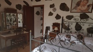 Ein Schlafzimmer mit Bett, Schreibtisch und Stuhl. An der Wand befinden sich dekorative Steine und ein gerahmtes Bild über dem Bett.