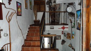 Eine rustikale Treppe mit Holzhandlauf, einer Uhr und verschiedenen Wanddekorationen, darunter gerahmte Bilder und ein Korb.