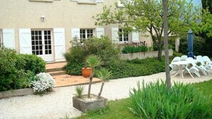 A two-story building with a garden patio, outdoor seating, and a gravel pathway.