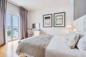 A bedroom with a bed, a desk, a chair, and two framed pictures on the wall.