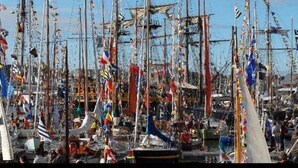 Un port animé où de nombreux bateaux sont amarrés, dont certains sont décorés de drapeaux aux couleurs vives.