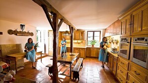 Uma cozinha rústica com armários de madeira, um fogão grande e uma área de refeições com bancos.