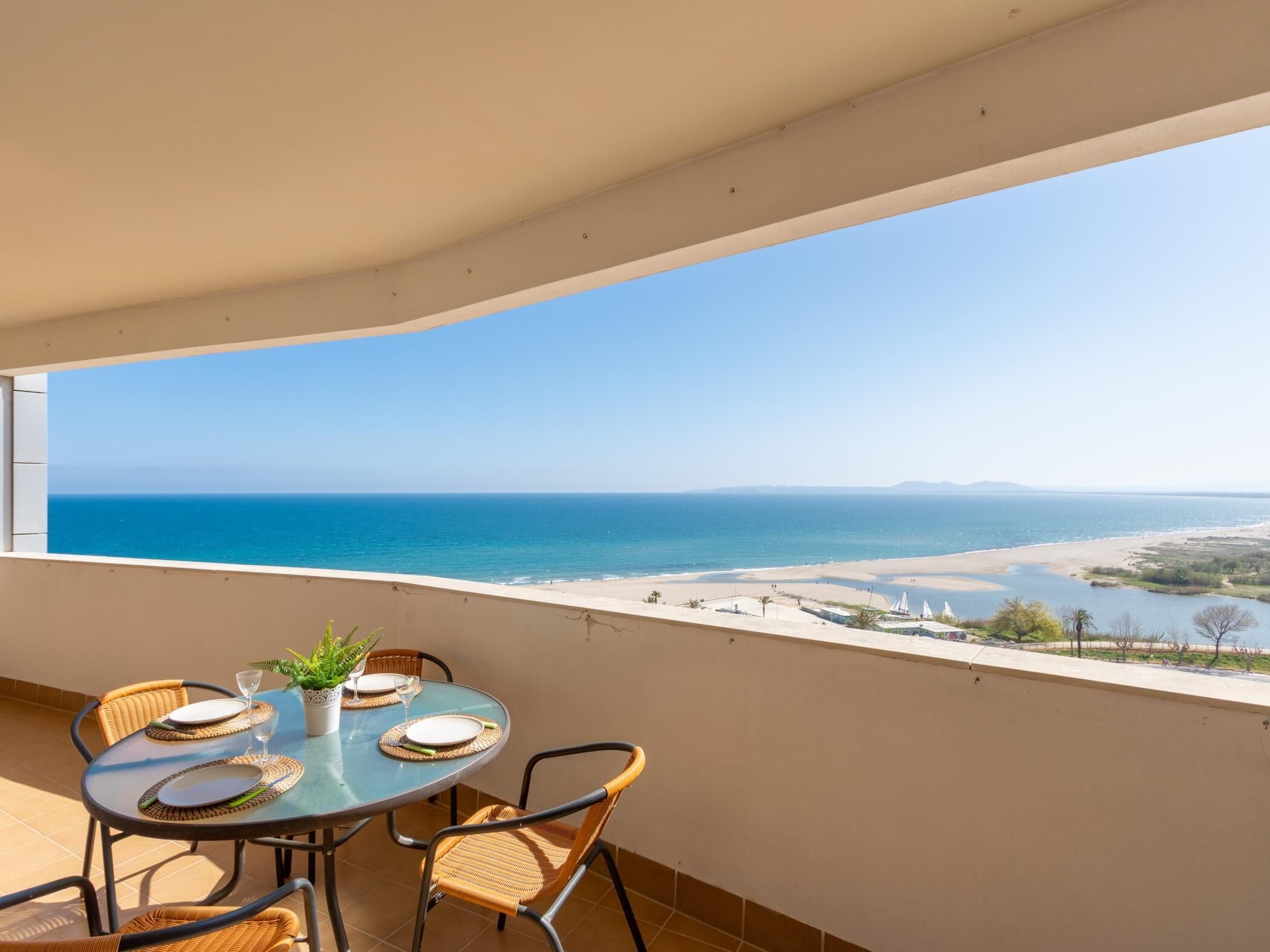 Un balcón con una mesa para dos personas, con vista a una playa y al océano.