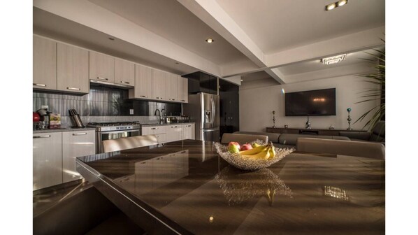 Modern kitchen with sleek cabinetry, stainless steel appliances, and a large island with a glass top.