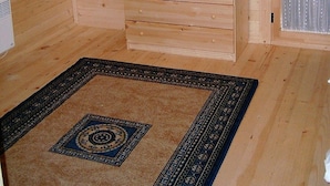 Una habitación de desván con techo inclinado, un pequeño aparador de madera, un espejo y una alfombra estampada.