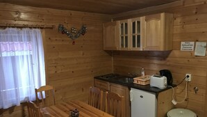Una cocina compacta con armarios de madera, un refrigerador pequeño, un tostador y un cubo de basura.