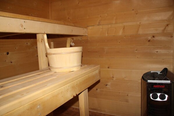 A wooden sauna with benches and a wooden bucket.