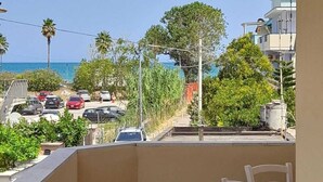 Ein Balkon mit Blick auf das Meer und geparkte Autos.