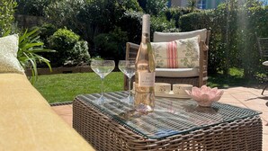 A wicker table with a bottle of wine, two wine glasses, and a decorative bowl. - Beautiful  Family Holiday Home  (La Môle)