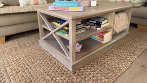 A wooden coffee table with books and a bottle of perfume on top. - Beautiful  Family Holiday Home  (La Môle)