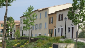 A row of multi-story buildings with uniform architecture, featuring balconies, windows with shutters, and a paved street in the foreground. - Beautiful  Family Holiday Home  (La Môle)