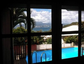 Overlooking the pool, lush gardens, and distant coastline, this room offers a serene view.