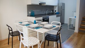 A modern kitchen with white cabinets, a stainless steel sink, and a built-in oven. There is a dining table set with plates, bowls, and cutlery. - House in the Historic Center of Cascais (Cascais)