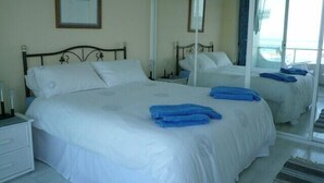 Une chambre d’hôtel avec deux lits, du linge de lit blanc et des serviettes bleues.