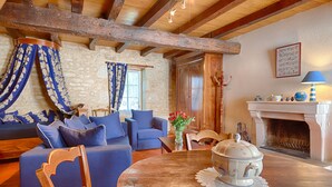 A cozy room with a stone wall, wooden beams, a fireplace, and blue furniture.