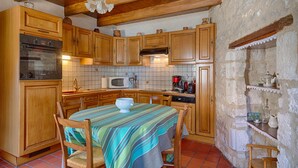A kitchen with wooden cabinets, a Bosch refrigerator, a microwave, a stove, and a dining table with chairs.