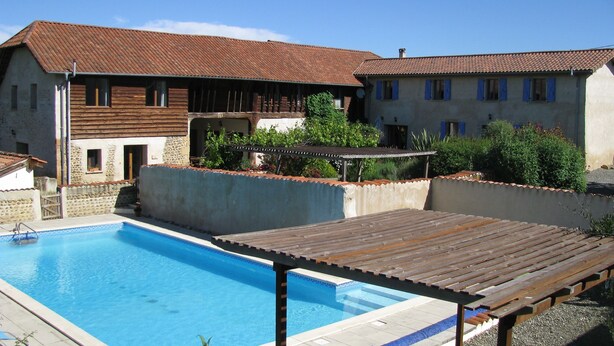 A swimming pool with a wooden deck, a stone wall, and a building with a tiled roof. - Peaceful private base in Pyrenees, large pool, perfect for outdoor enthusiasts (Thuy)