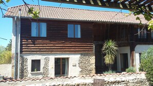 A two-story building with a tiled roof, stone walls, and wooden logs on the lower level. - Peaceful private base in Pyrenees, large pool, perfect for outdoor enthusiasts (Thuy)
