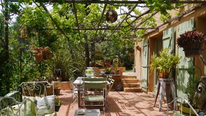 A covered patio area with a table and chairs, surrounded by potted plants and a pergola with hanging decorations. - Pinarello: CHARMING HOUSE 400m FROM THE BEACH, SWIMMING POOL AND SPA (Zonza)
