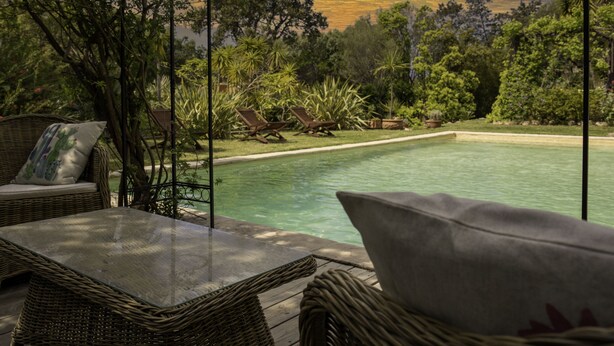 An outdoor seating area with wicker furniture and a view of a swimming pool surrounded by lush greenery. - Pinarello: CHARMING HOUSE 400m FROM THE BEACH, SWIMMING POOL AND SPA (Zonza)