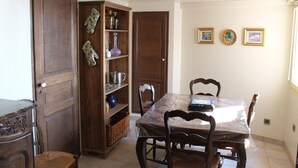 Zona pranzo con tavolo in legno, sedie e un mobiletto contenente stoviglie.