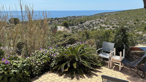 Un patio con sedie affacciato su un paesaggio costiero.