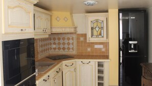 Cucina con pensili bianchi, forno nero e frigorifero nero.