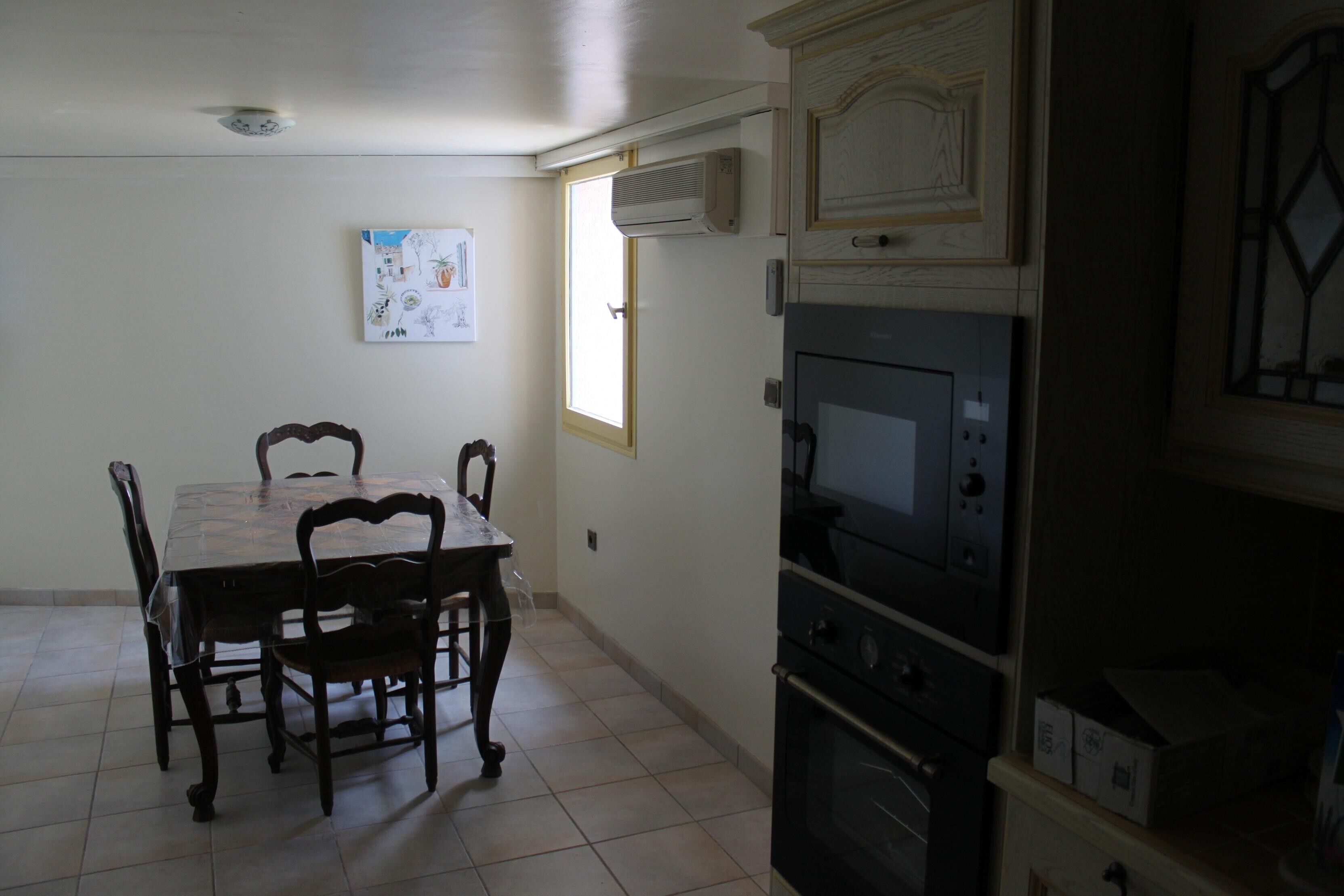 A kitchen with a dining table and chairs, an oven, a microwave, and a window with a door.