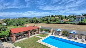A pool area with a stone deck, a barbecue area, and a view of the surrounding landscape. - Acharavi Beach Villa - Luxury Seaside Villa Rental in Acharavi, Island of Corfu. (Acharavi)