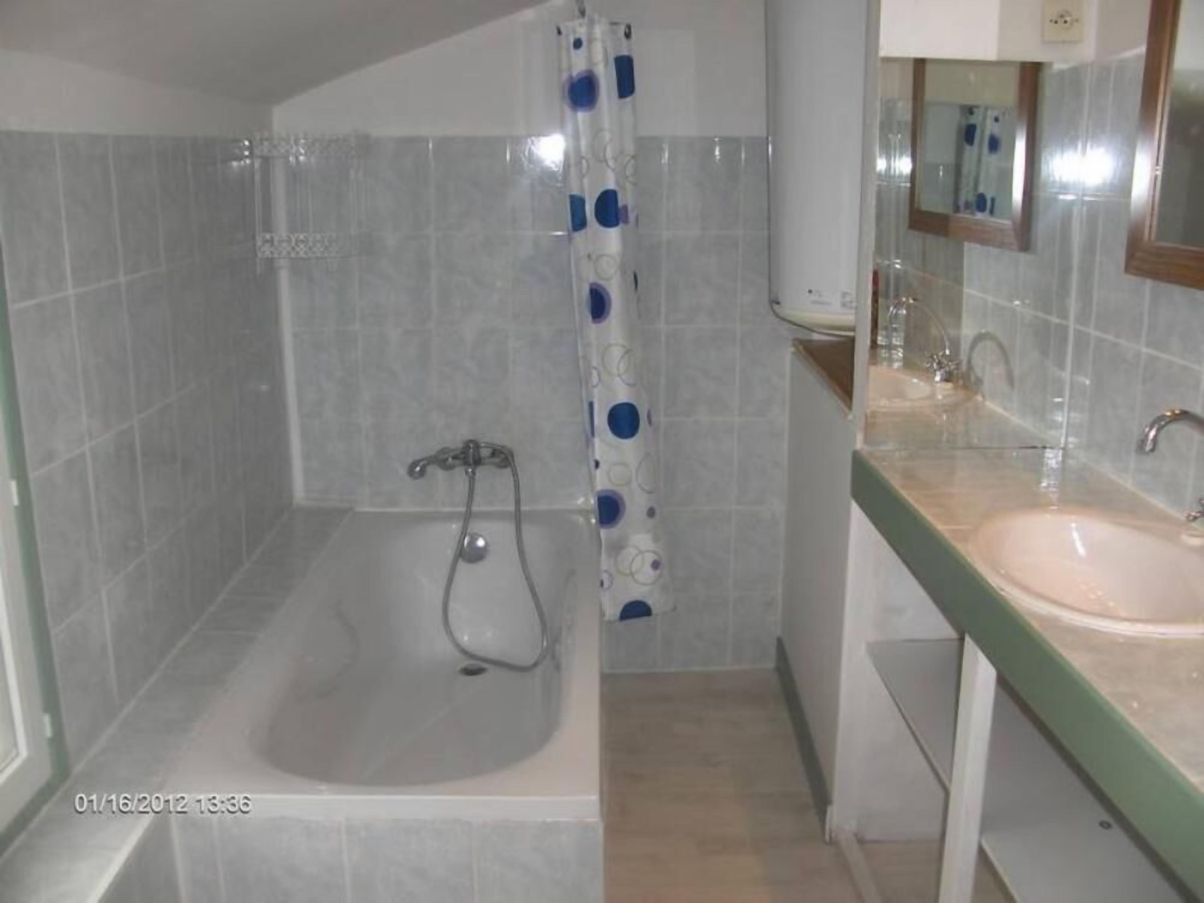Un baño con bañera, ducha y lavamanos con espejo.