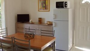 A small kitchen with a microwave, a television, and a refrigerator. There is a dining table with chairs and a window providing natural light. - Apartment/ flat - Pieve (Piève)