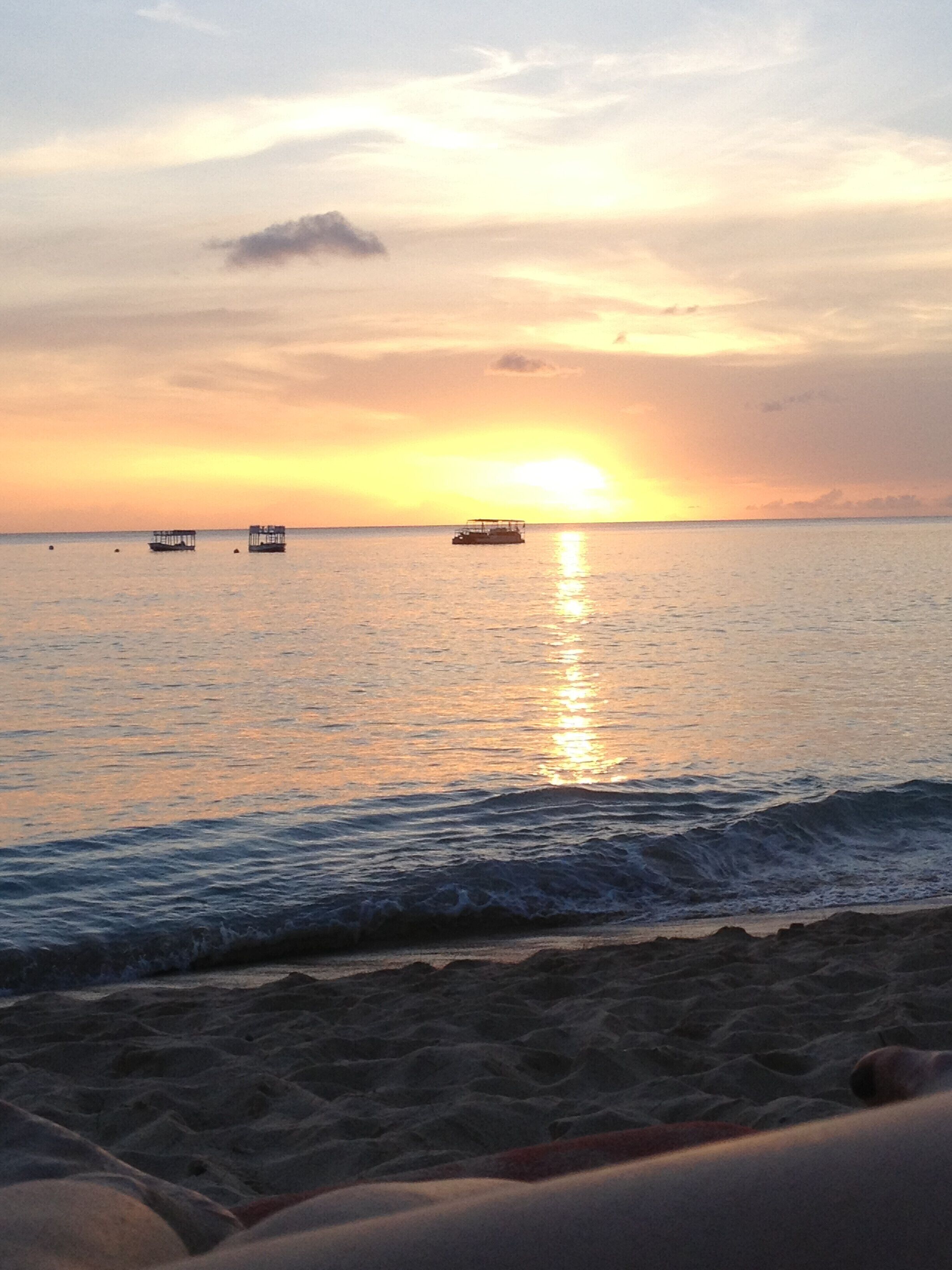 A beach with calm waters and a sunset.