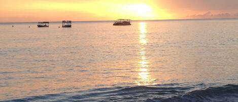 A beach with calm waters and a sunset.