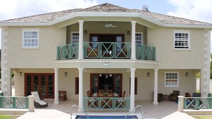 A two-story house with a pool, a balcony, and a dining area. - 4 Bed Colonial Style Villa with pool in private setting, short walk to 2 beaches (Gibbes)
