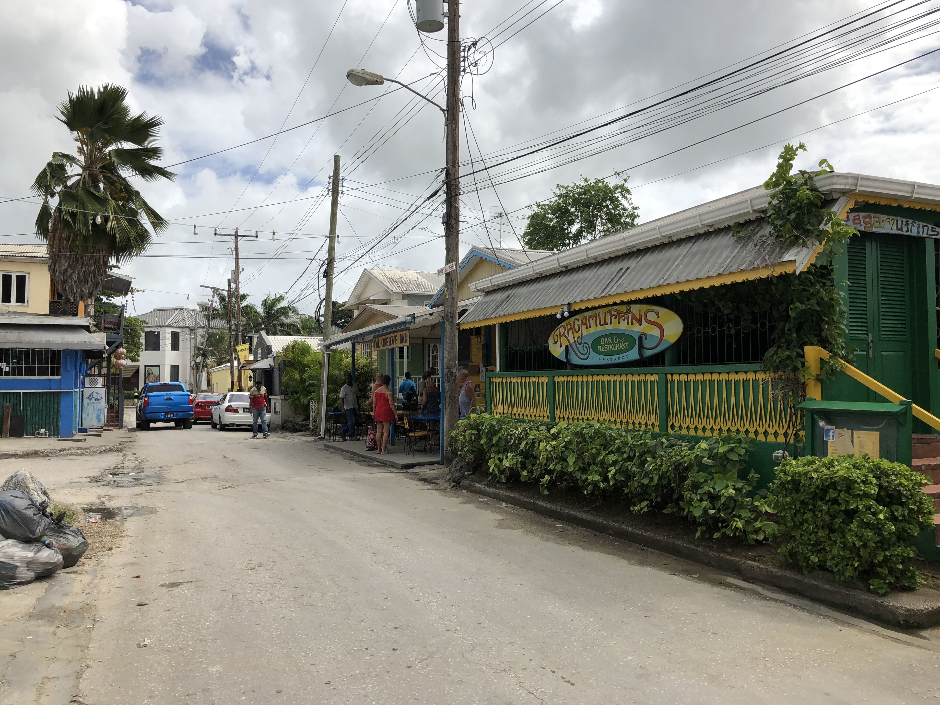 A street view with a restaurant named 'Ragamuffins Bar & Restaurant' and a blue car parked on the side.