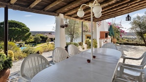 A covered outdoor dining area with a table and chairs, a hanging lantern, and a view of a pool and landscape. - House Countryside with view on the Dam, with Pool, lawn, Barbecue, porch (Barragem de Montargil)