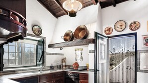 A kitchen with a large window, wooden cabinets, a Bosch dishwasher, and a hanging pot rack. - House Countryside with view on the Dam, with Pool, lawn, Barbecue, porch (Barragem de Montargil)