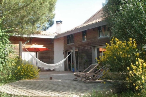 Vue d'ensemble de la maison depuis le jardin, avec la terrasse en premier plan
