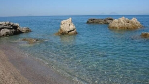 Ein Strand mit klarem Wasser und Felsformationen.