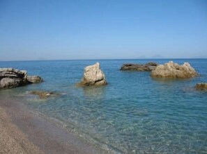A beach with clear water and rocky formations. - OLIVE TREE CHALET: • wi-fi • garden • bbq •veranda • amazing sea and hills view (Rocca di Capri Leone)