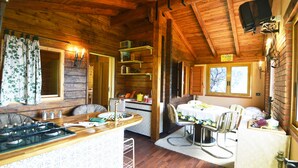 Ein Interieur einer Holzhütte mit Küche, Essbereich und einer kleinen Wohnstube.