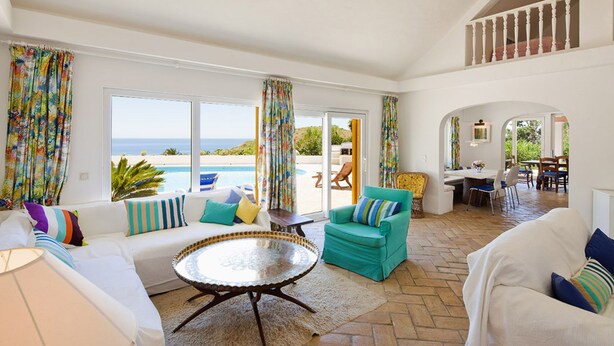 Un'ampia zona giorno con vista mare, una sala da pranzo e un balcone con piscina.