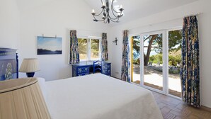 Una camera da letto con un letto grande, una cassettiera, una lampada e vista sull'esterno tramite una porta scorrevole in vetro.