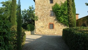 Edifici de pedra amb un camí de grava, envoltat d'alzines i vegetació.