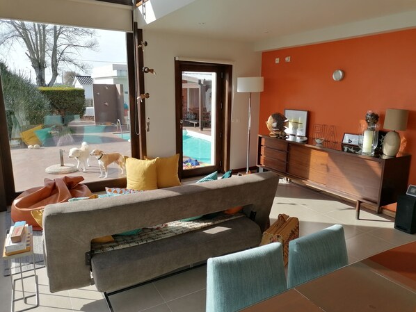 Una sala de estar moderna con un sofá, una mesa de centro y vistas a una piscina.