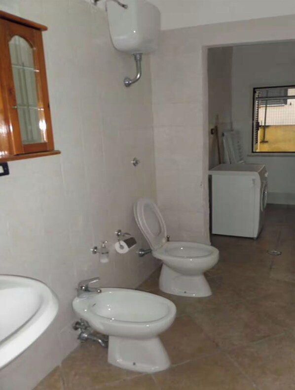 A bathroom with two toilets, a sink, and a window.