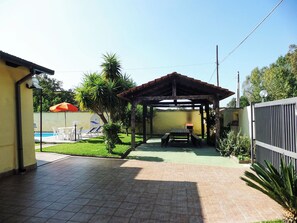 Ein überdachter Patio-Bereich mit Pool, Gartenmöbeln und einem kleinen Tisch.