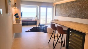 A modern kitchen with a bar area, a dining table, and a view of the ocean. - Maramar Westend Luxury Apartment with Sea View (Middelkerke)