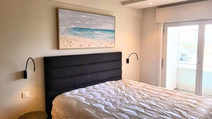A bedroom with a bed, a painting of a beach scene, and a door leading to a balcony. - Maramar Westend Luxury Apartment with Sea View (Middelkerke)