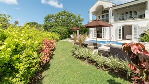 A well-maintained garden with a swimming pool, a white house with a balcony, and a clear blue sky. - Sugar Cane Ridge 23 (St James)